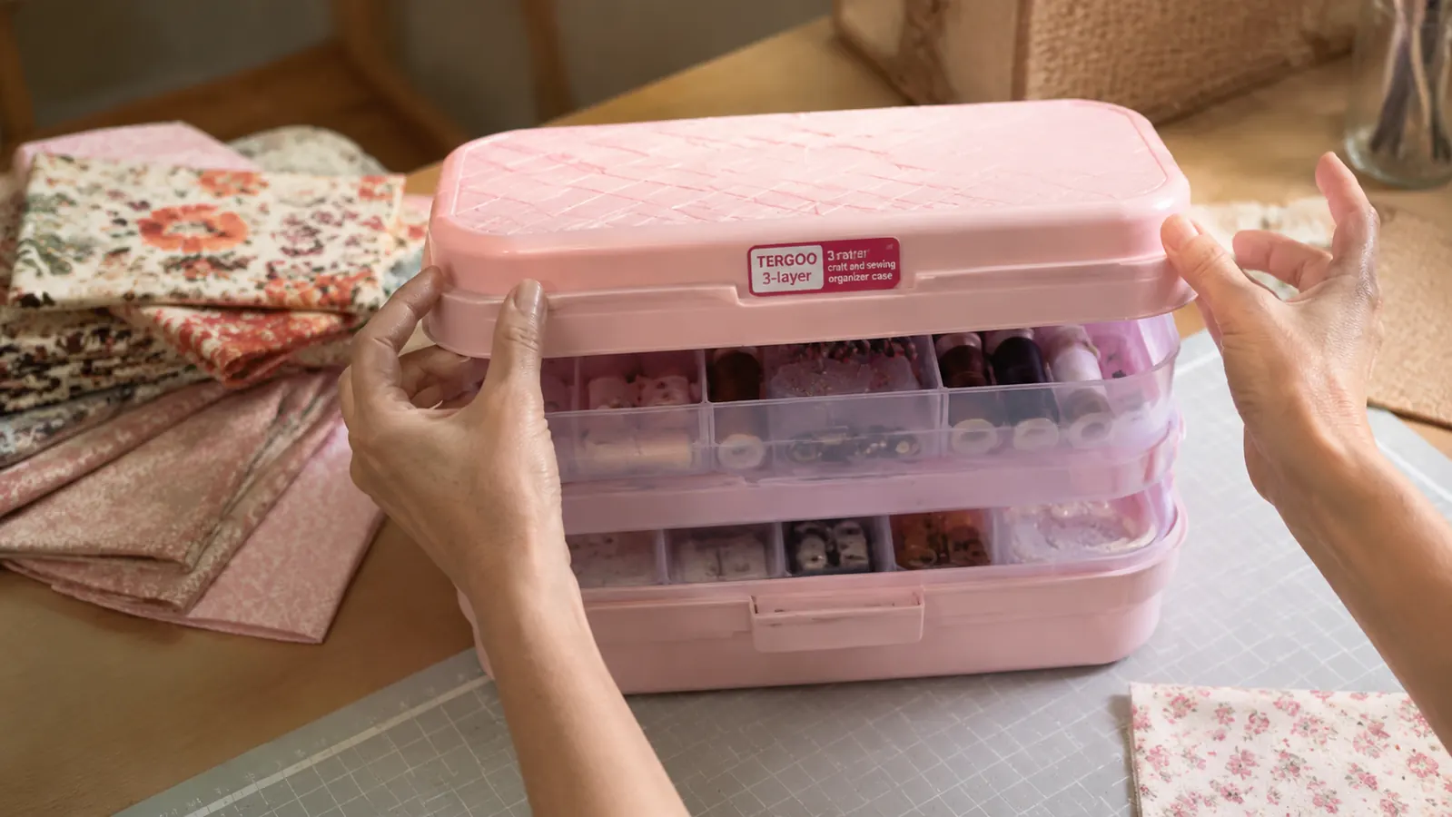 Woman's hands lifting the top layer of a craft organizer to reach sewing notions in the middle tier